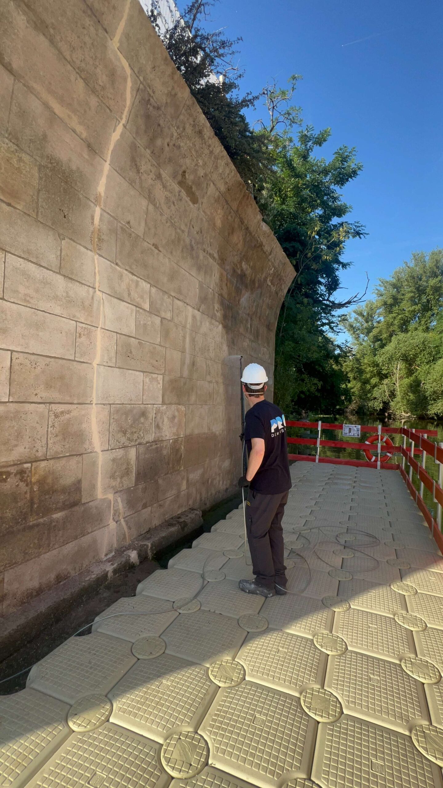 Technicien Pro Démoussage sur un chantier de nettoyage de mur en pierre
