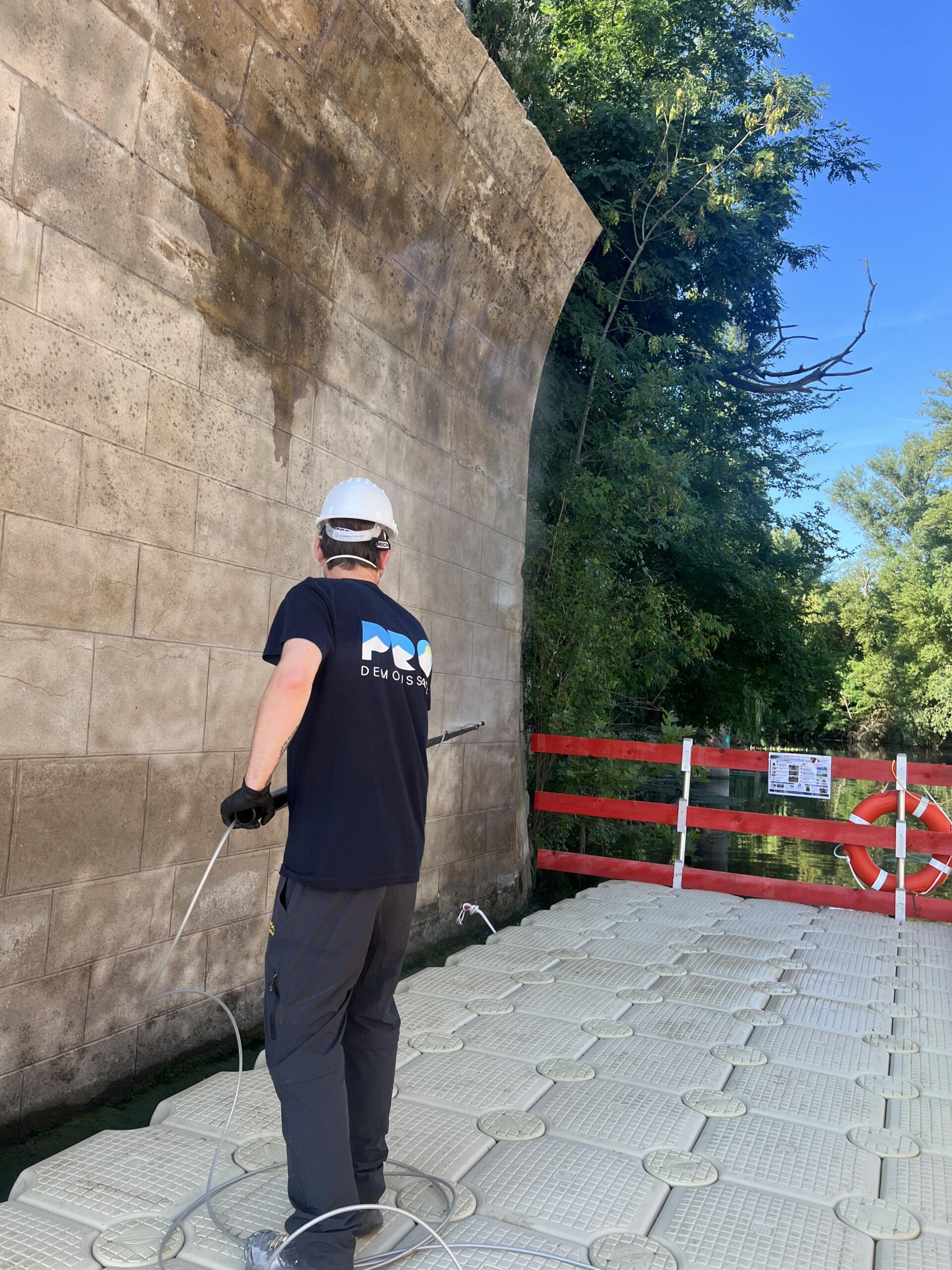 Technicien Pro Démoussage traitant un mur en pierre dans le Nord